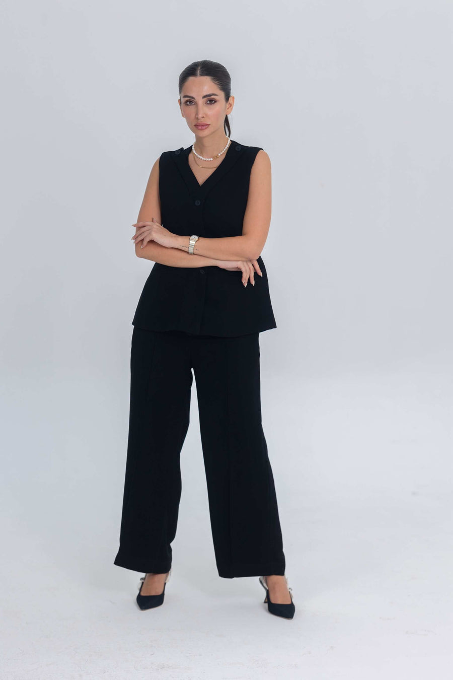 Woman wearing a plain black sleeveless crepe inner set with wide-leg pants and black heels against a white background