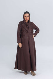 Woman wearing a brown linen abaya with blazer collar and floral lace embroidery patches, designed for lightweight summer wear.
