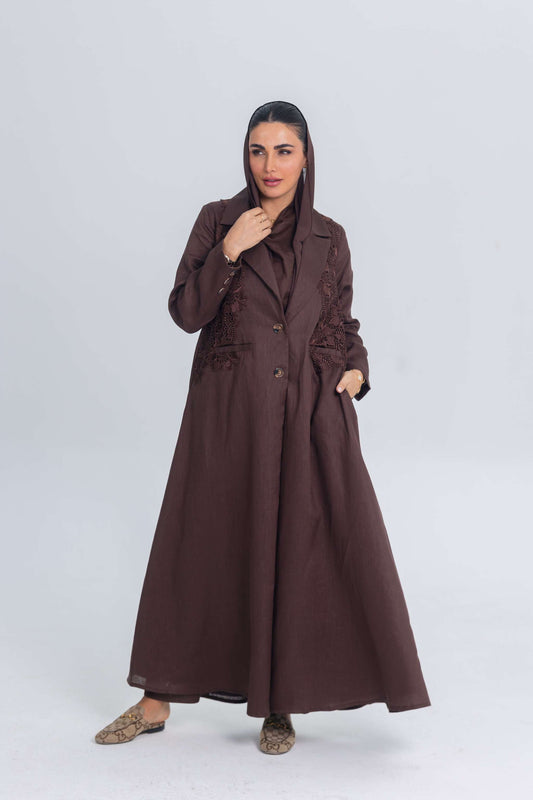 Woman wearing a brown linen abaya with blazer collar and floral lace embroidery patches on the sides