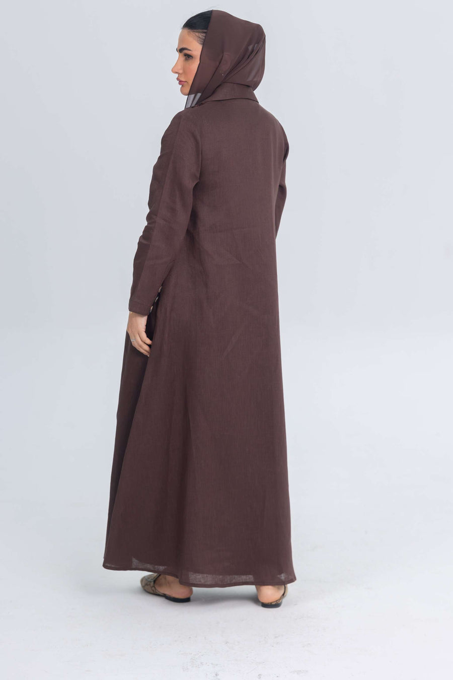 Woman wearing brown linen abaya with blazer collar and floral lace embroidery patches, back view
