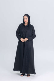 Woman wearing Black Mirage black linen abaya with textured fabric and hood, styled for modest modern elegance