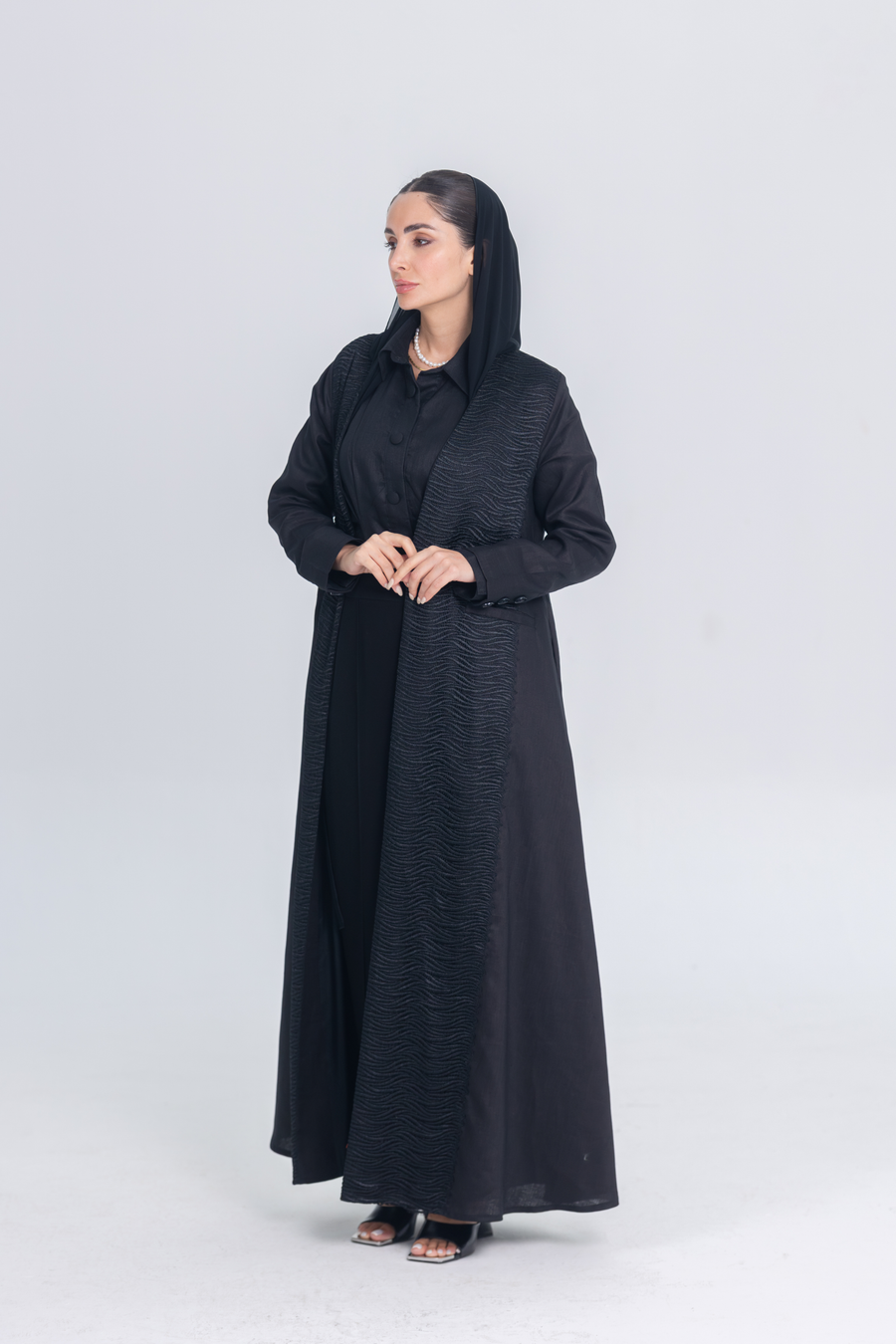 Elegant black linen abaya with textured fabric detail and matching inner set, worn with black headscarf.