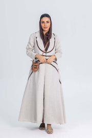 Woman wearing beige linen abaya with brown trim and matching headscarf, carrying a small plaid crossbody bag