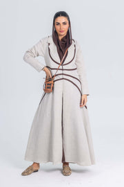 woman wearing beige linen abaya with brown brim and matching brown hijab carrying a small tan crossbody bag