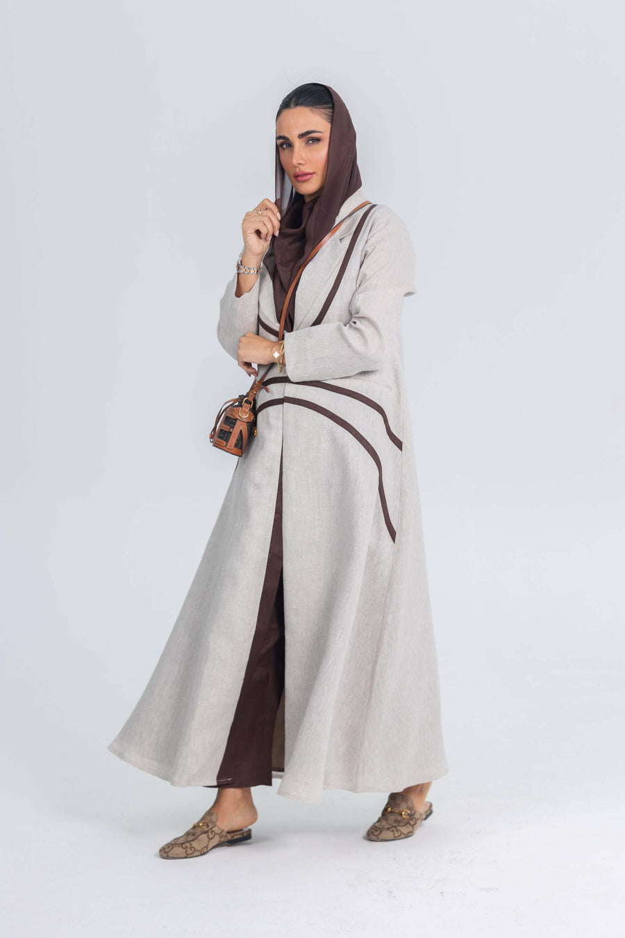 Beige linen abaya with brown brim detailing worn with matching brown hijab and shoes