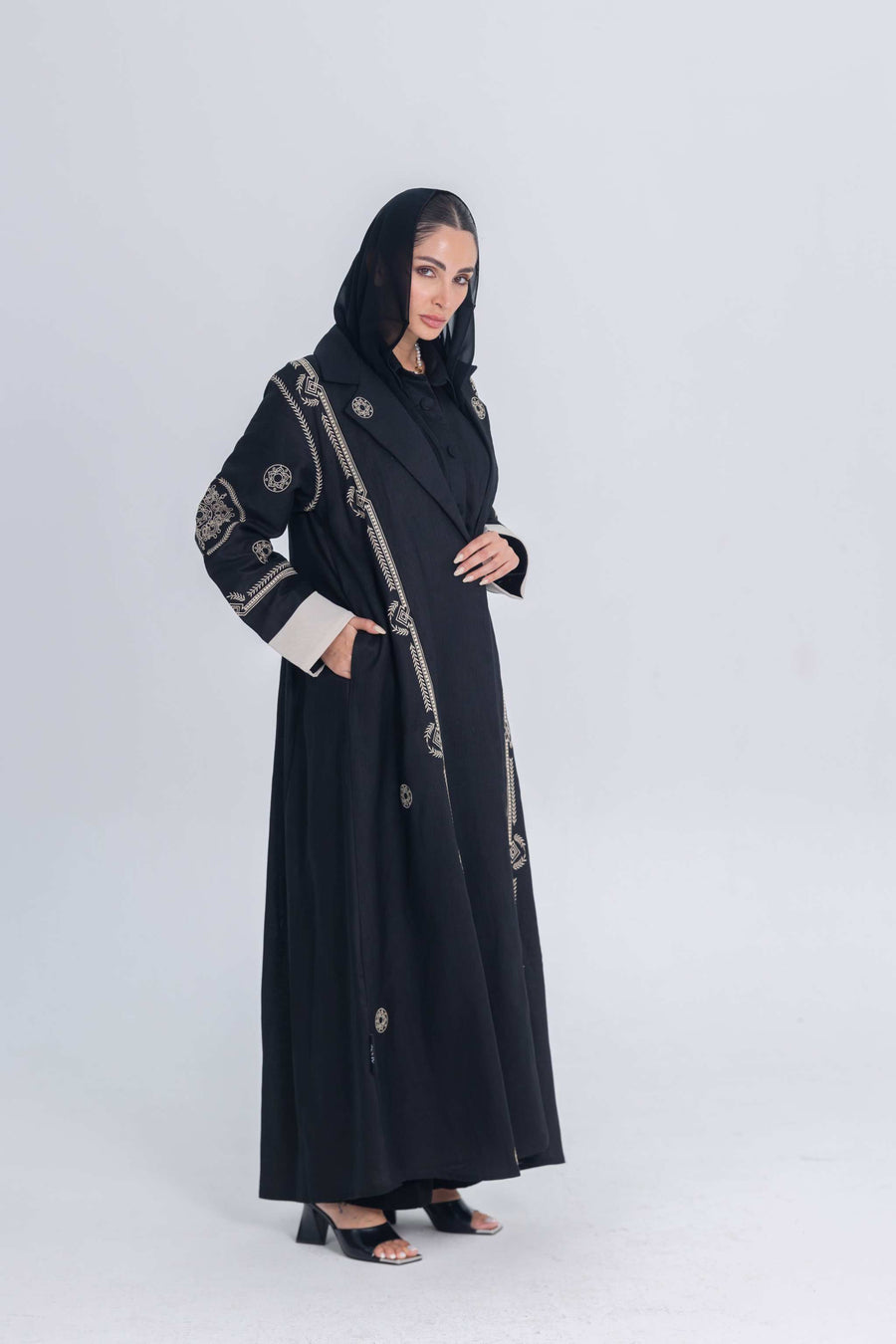 Black luxury linen abaya with beige circular embroidery and structured flowing design worn by woman