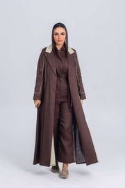 Woman wearing a brown linen abaya with soft mint green panels, featuring clean lines and refined detailing for a modern, elegant look.