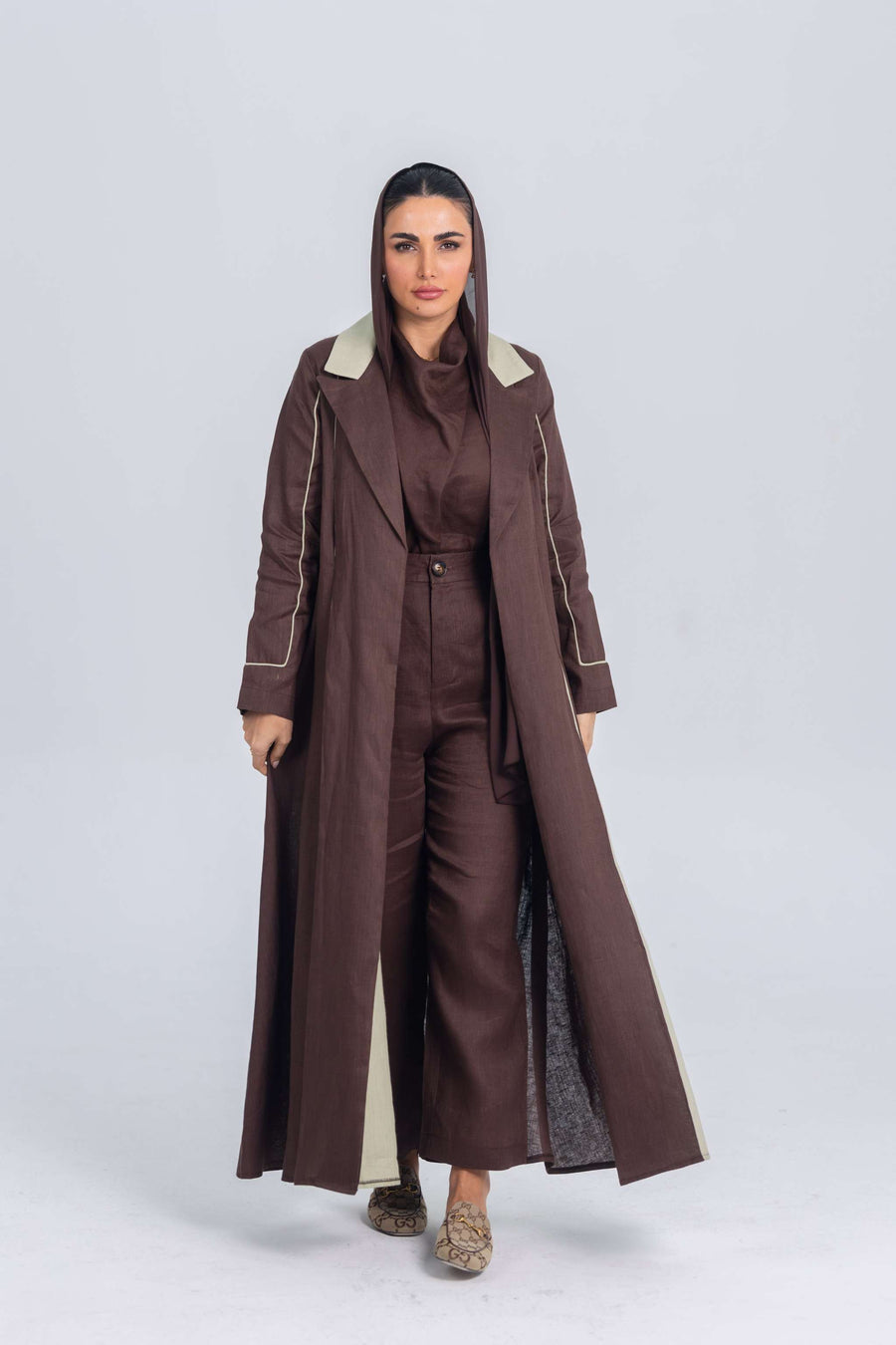 Woman wearing a brown linen abaya with soft mint green panels, featuring clean lines and refined detailing for a modern, elegant look.
