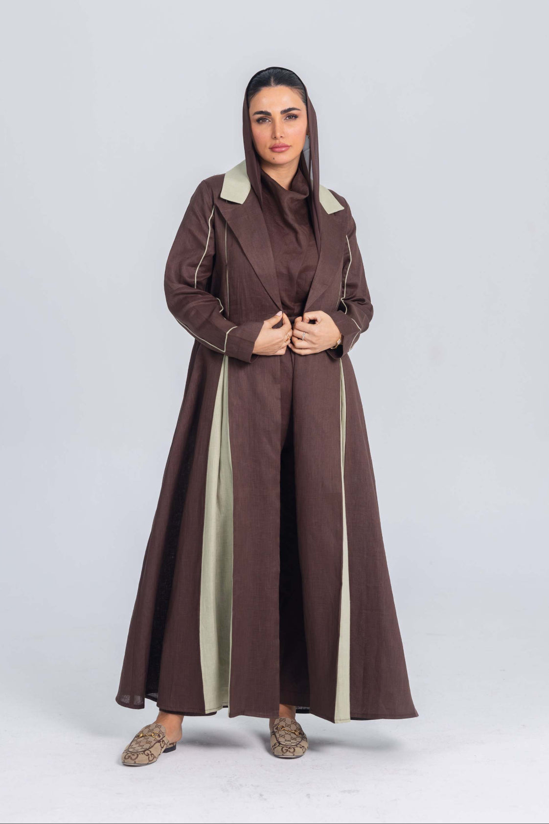 Woman wearing a brown linen abaya with soft mint green panels and clean lines, styled with modest elegance.