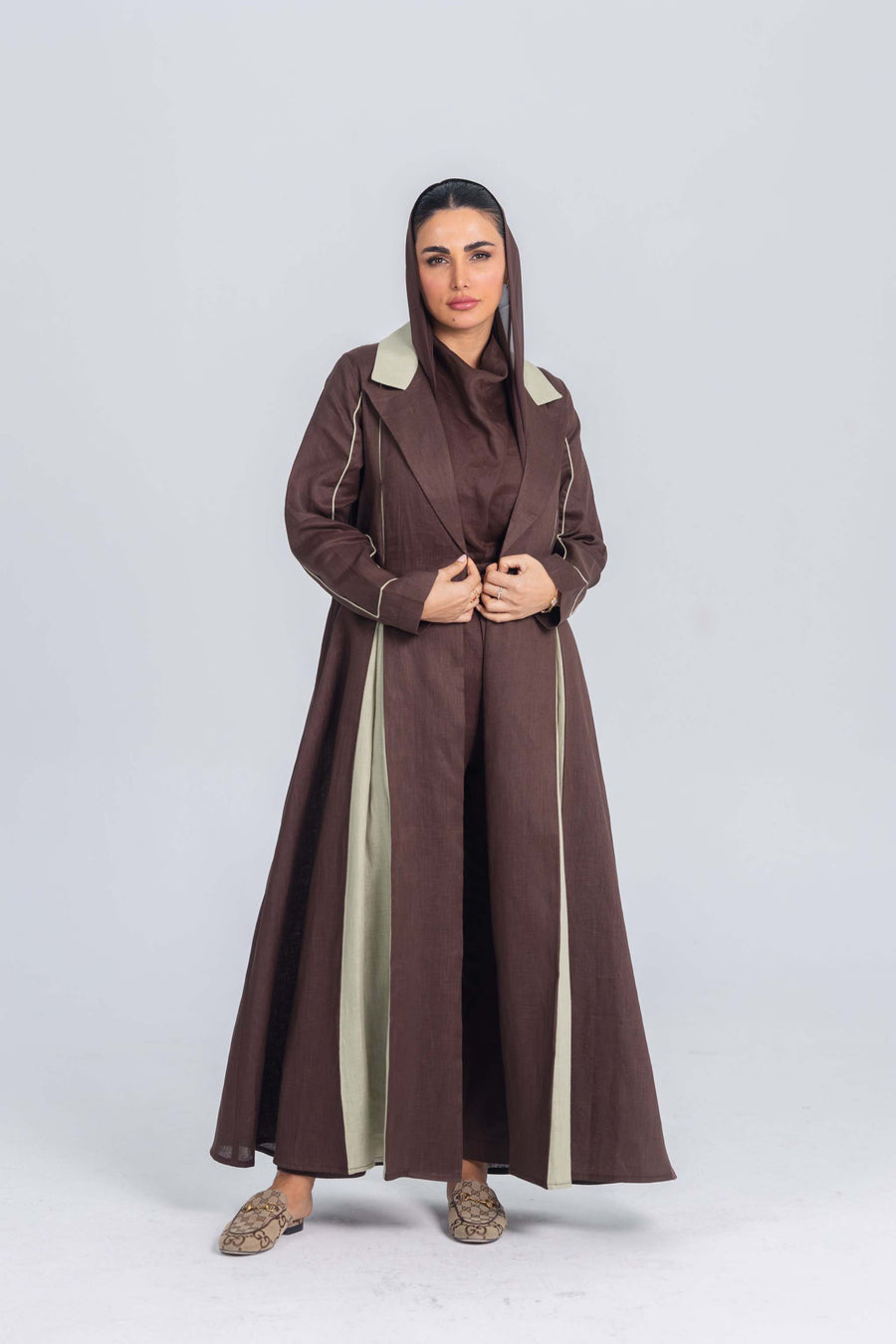 Woman wearing a brown linen abaya with soft mint green panels and clean lines, styled with modest elegance.