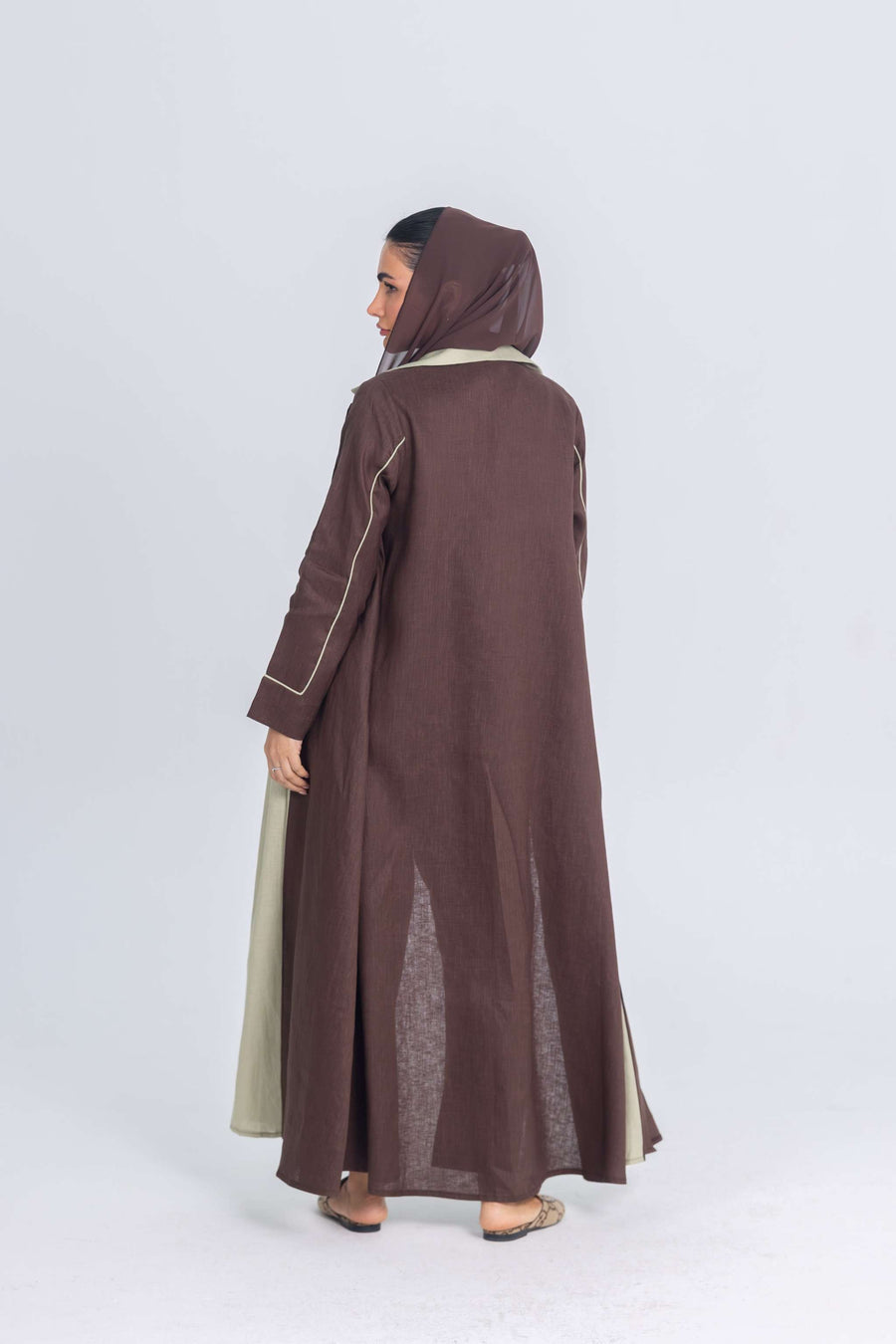 Woman wearing a brown linen Mint Mocha abaya with soft mint green panels and a matching hood, showcasing a modern and sophisticated design.