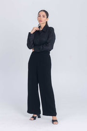 Woman wearing black Essence Folds shirt with pleated chest and black wide-leg pants