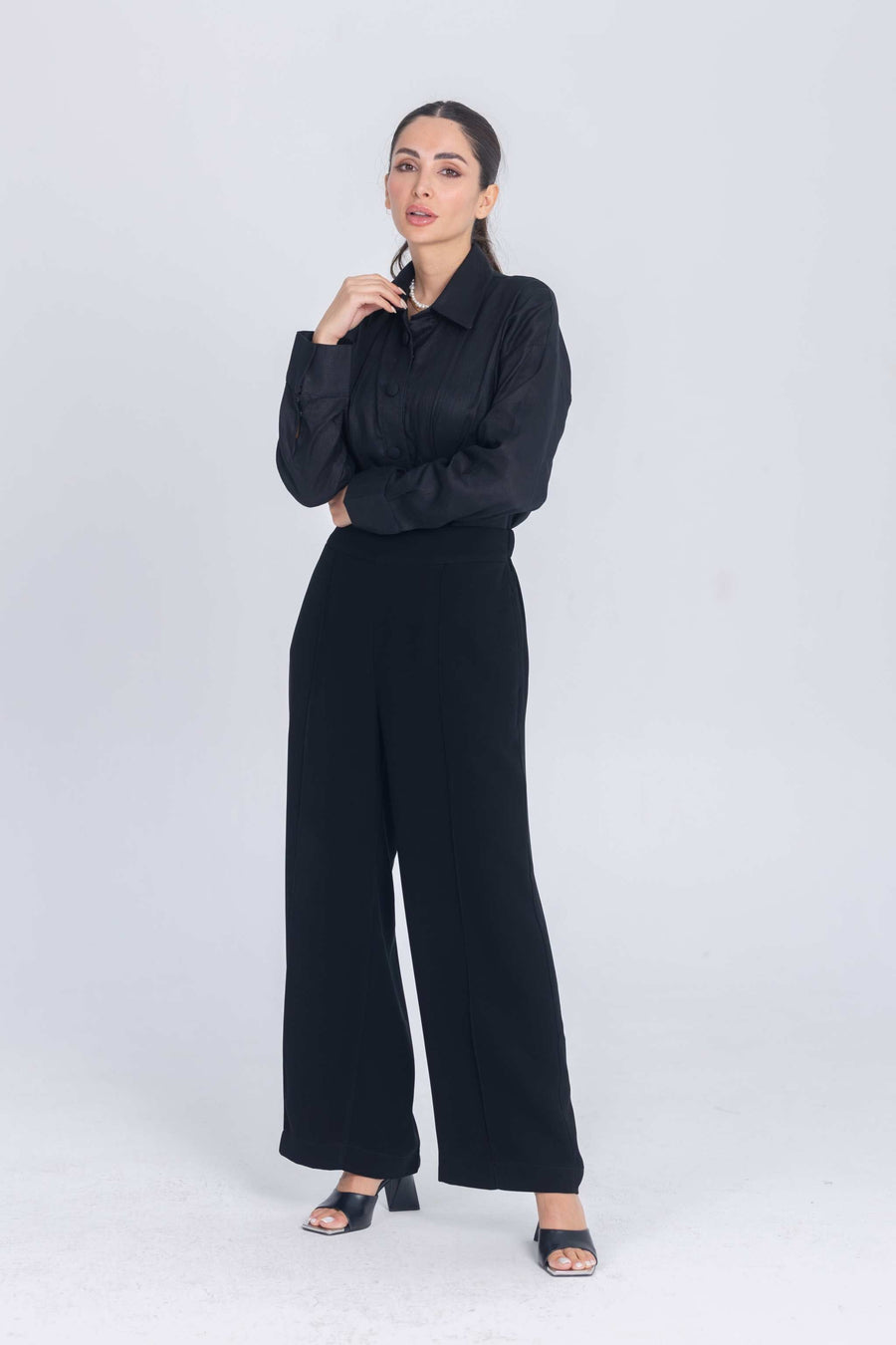 Woman wearing black Essence Folds shirt with pleated chest and black wide-leg pants