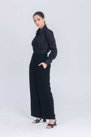 Woman wearing black Essence Folds shirt with pleated chest and wide-leg pants