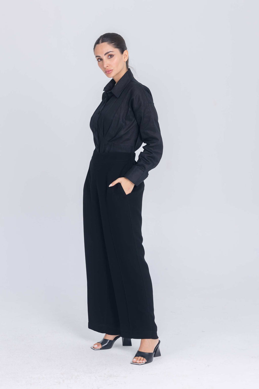 Woman wearing black Essence Folds shirt with pleated chest and wide-leg pants