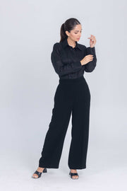 Woman wearing black Essence Folds shirt with chest pleats and black wide-leg pants