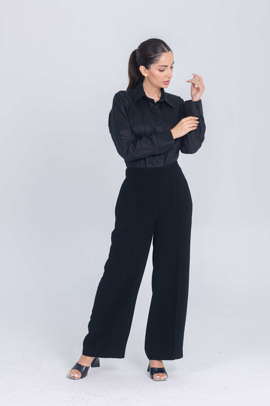 Woman wearing black Essence Folds shirt with chest pleats and black wide-leg pants