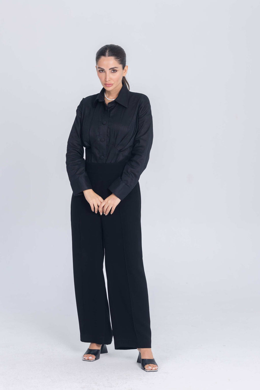 Woman wearing black Essence Folds shirt with chest pleats and black wide-leg pants