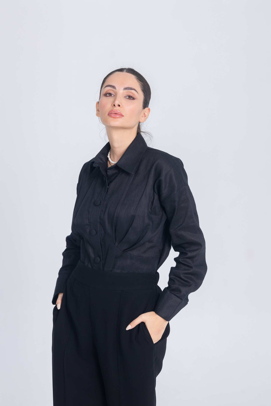 Woman wearing black Essence Folds shirt with pleated chest detail and long sleeves