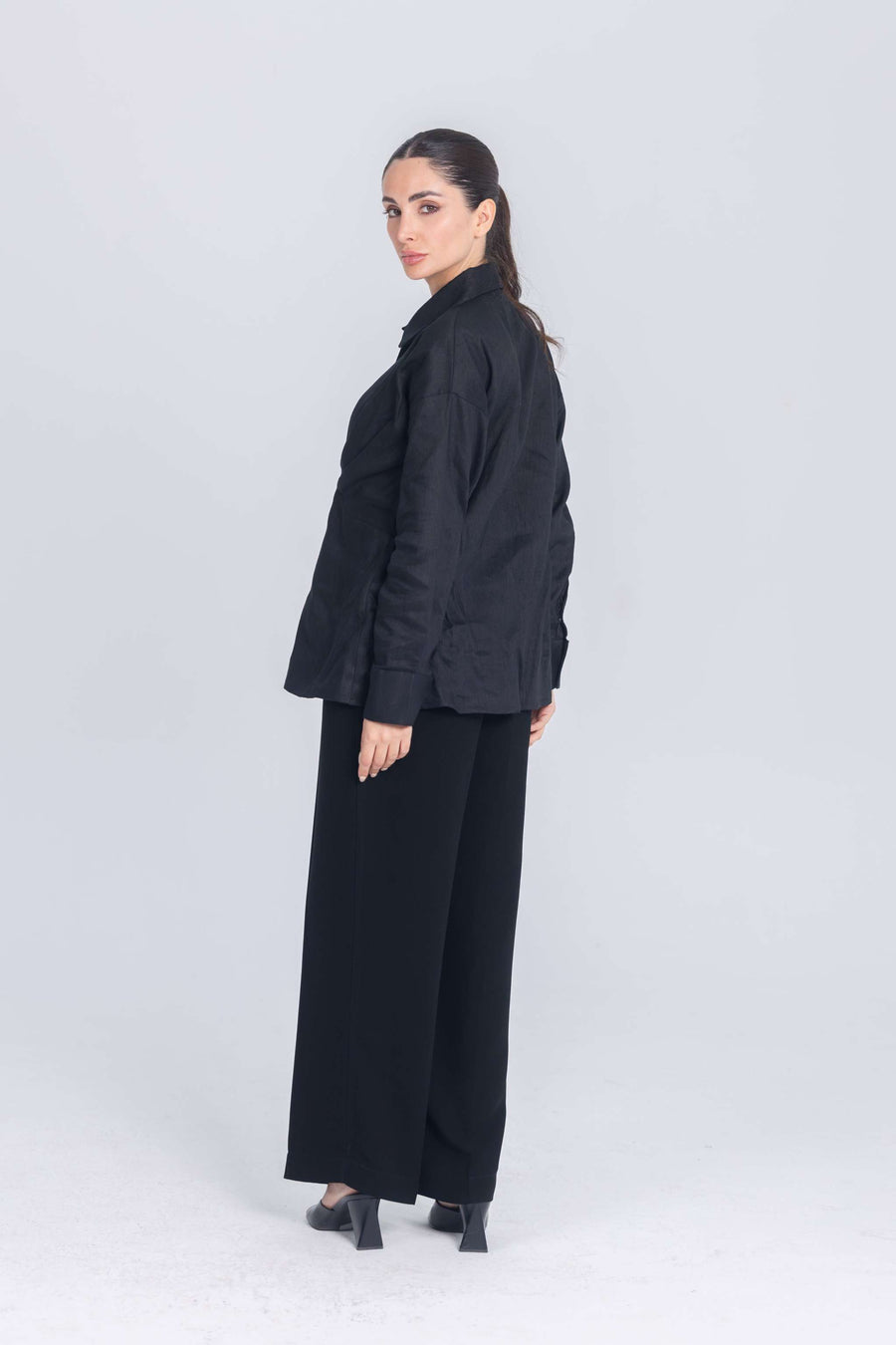 Woman wearing black Essence Folds shirt with pleated chest and black wide-leg pants