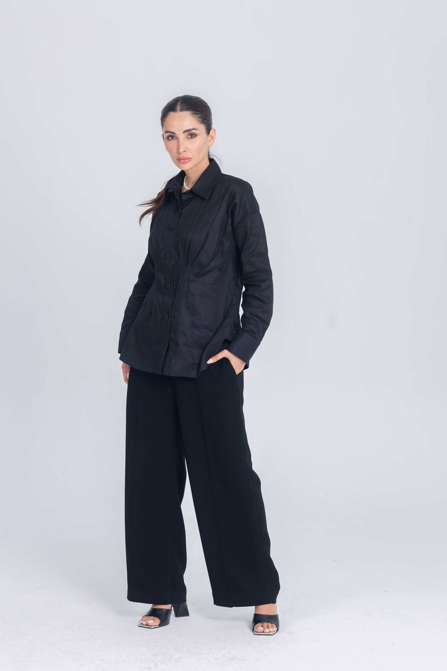 Woman wearing black Essence Folds shirt with chest pleats and black wide-leg pants