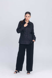 Woman wearing Essence Folds black shirt with chest pleat detail and black wide-leg pants