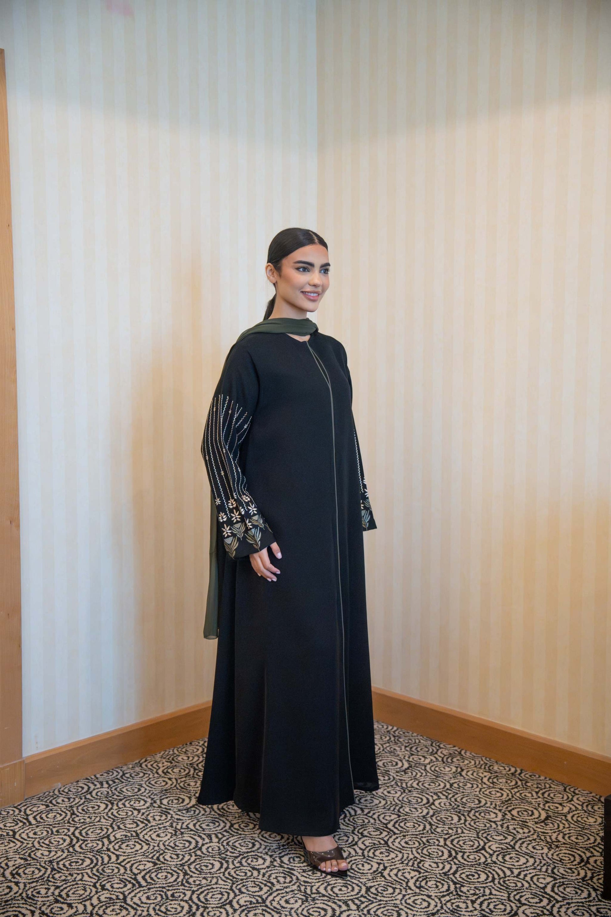 Woman wearing Classic Straight-Cut Black Abaya with olive green trim and embroidered floral statement sleeves.