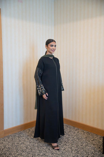 Woman wearing Classic Straight-Cut Black Abaya with olive green trim and embroidered floral statement sleeves.