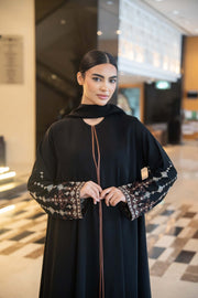 Elegant flowing black abaya with straight cut, round neckline, and embroidered wide sleeves.