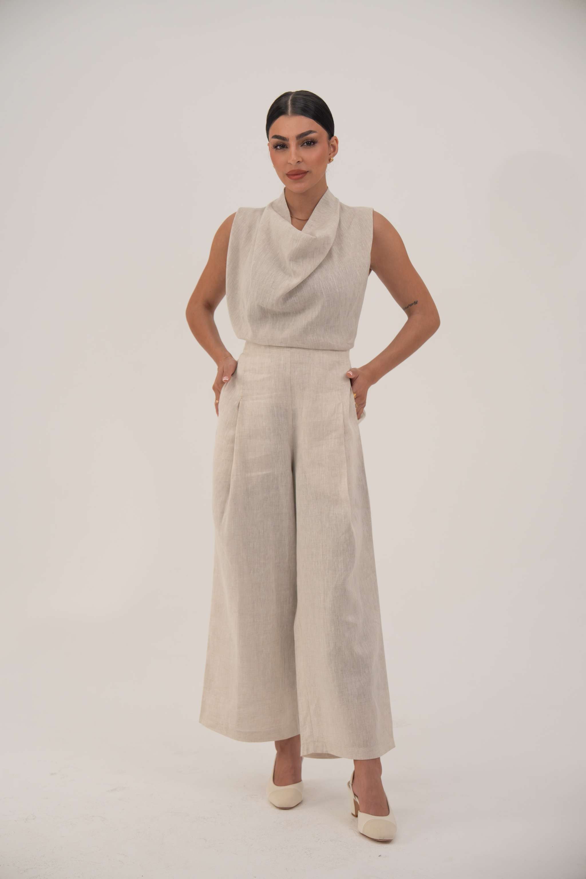 woman wearing sleeveless beige blouse with cowl neckline and matching wide-leg pants