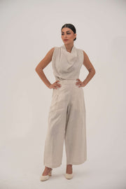 Woman wearing beige linen wide leg pants with a sleeveless beige top and heels in a studio setting