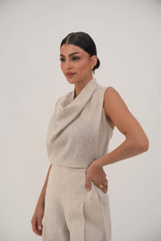 Woman wearing a sleeveless beige blouse with a draped cowl neckline and high-waisted wide-leg pants