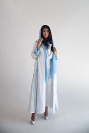 White linen blazer abaya with blue triangular embroidery and soft blue chiffon inner layer, worn with matching blue headscarf.