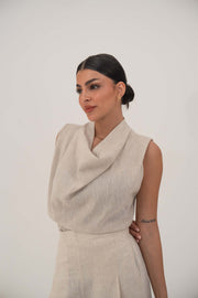 Woman wearing a sleeveless beige blouse with a draped cowl neckline and high-waisted wide-leg pants