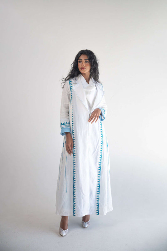 White linen blazer abaya with blue triangular embroidery and soft blue chiffon inner layer worn by model