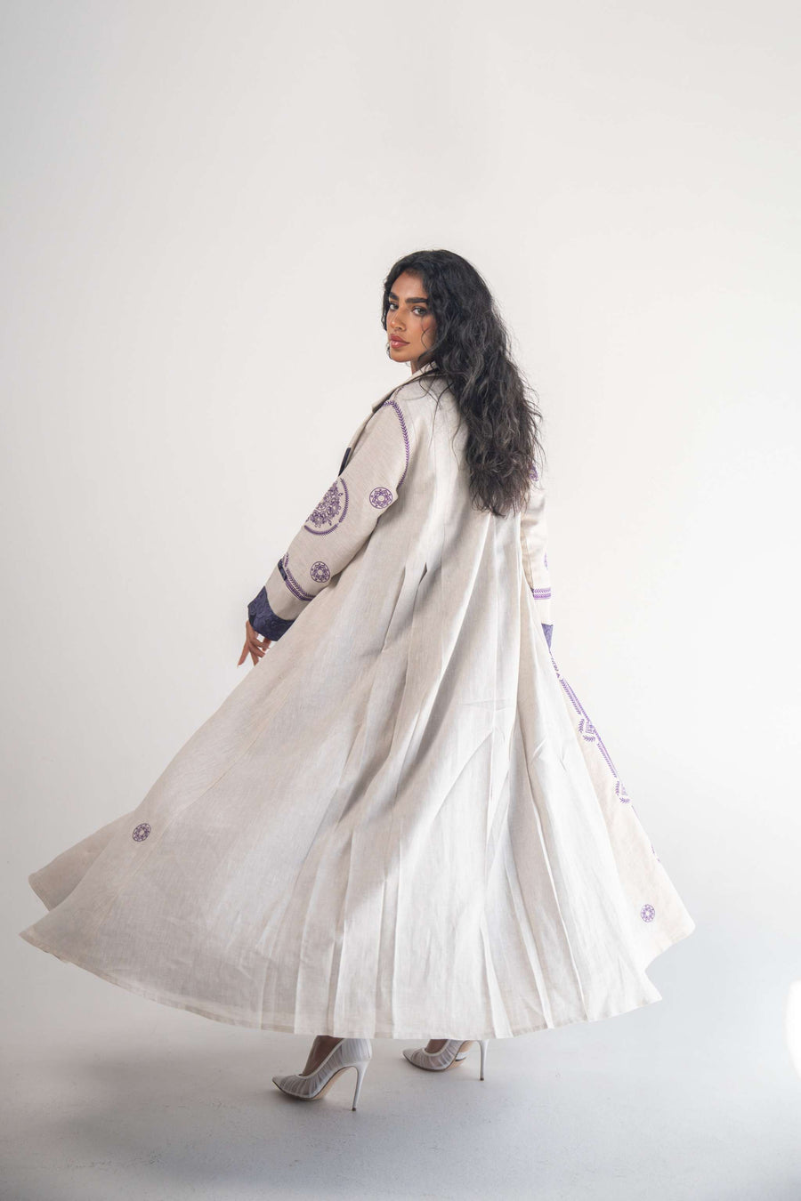 Beige linen blazer abaya with purple geometric and circular embroidery, classic collar, back pleats, and soft purple chiffon inner layer.