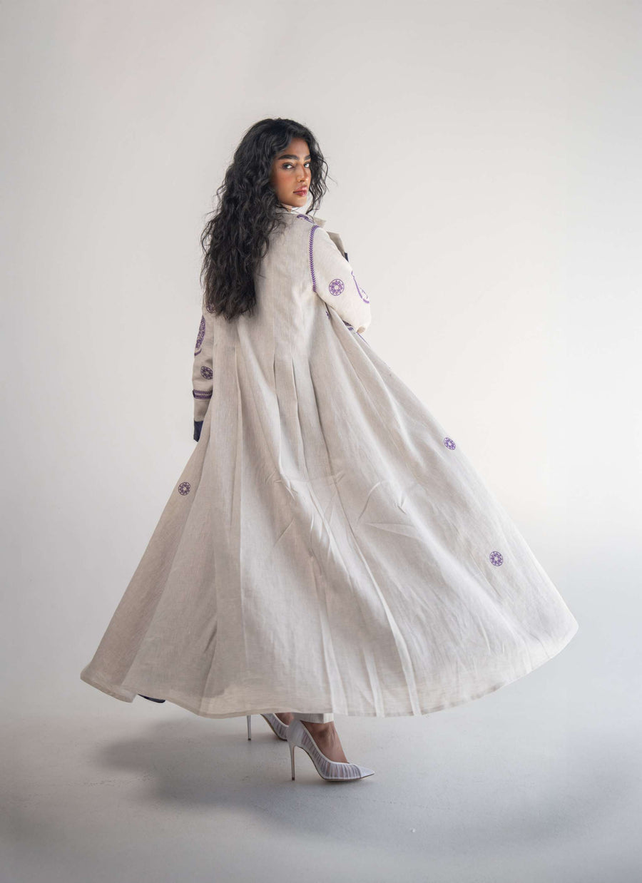 Beige linen blazer abaya with purple geometric and circular embroidery, chiffon inner layer, and pleated back detail worn by a woman with high heels