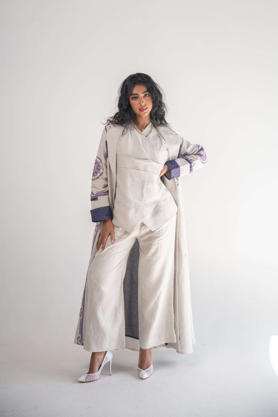 Elegant soft beige linen blazer abaya with intricate purple geometric and circular embroidery on sleeves, sides, and back, featuring a classic collar and purple chiffon inner layer.