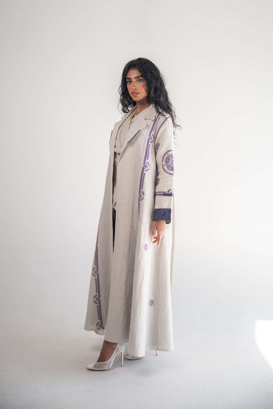 Woman wearing beige linen blazer abaya with purple geometric embroidery and chiffon inner layer