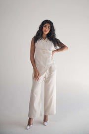 Woman wearing sleeveless almond beige blouse with wrapped front and soft pleats paired with matching wide-leg pants