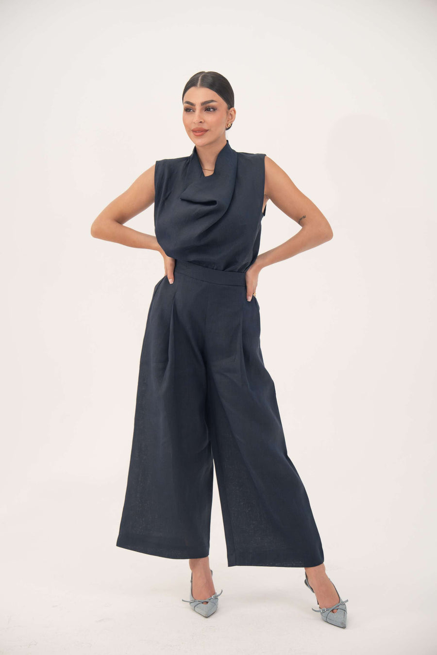 Woman wearing indigo wide leg high-waisted linen pants with front pleats and hidden pockets