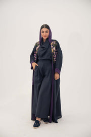 woman wearing navy blue linen-blend abaya with hand-stitched floral details and purple cuffs