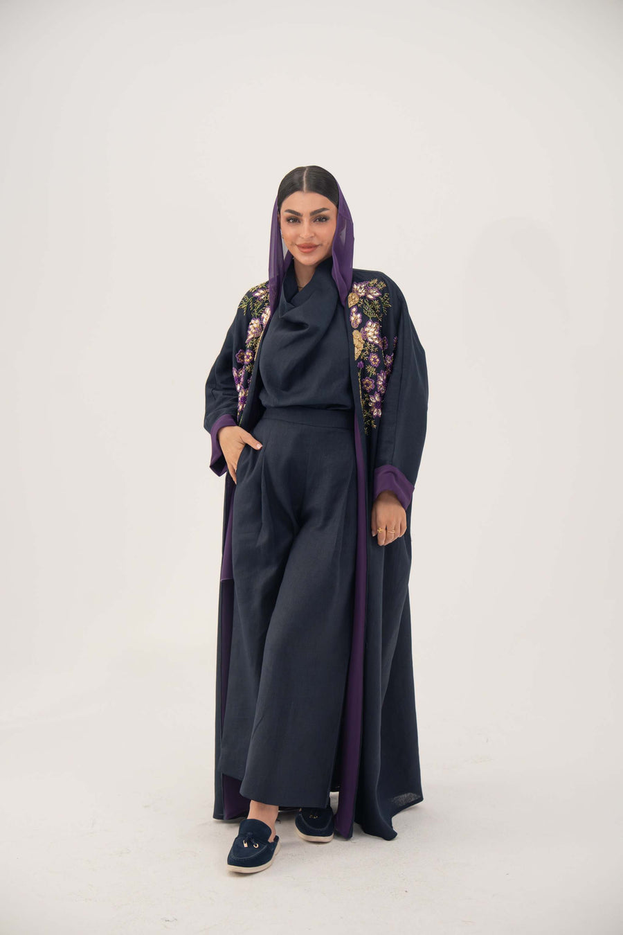 woman wearing navy blue linen-blend abaya with hand-stitched floral details and purple cuffs
