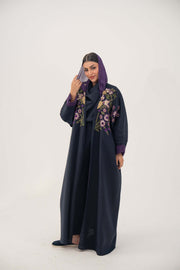 woman wearing navy blue linen-blend abaya with purple, gold, and green hand-stitched floral details and purple cuffs