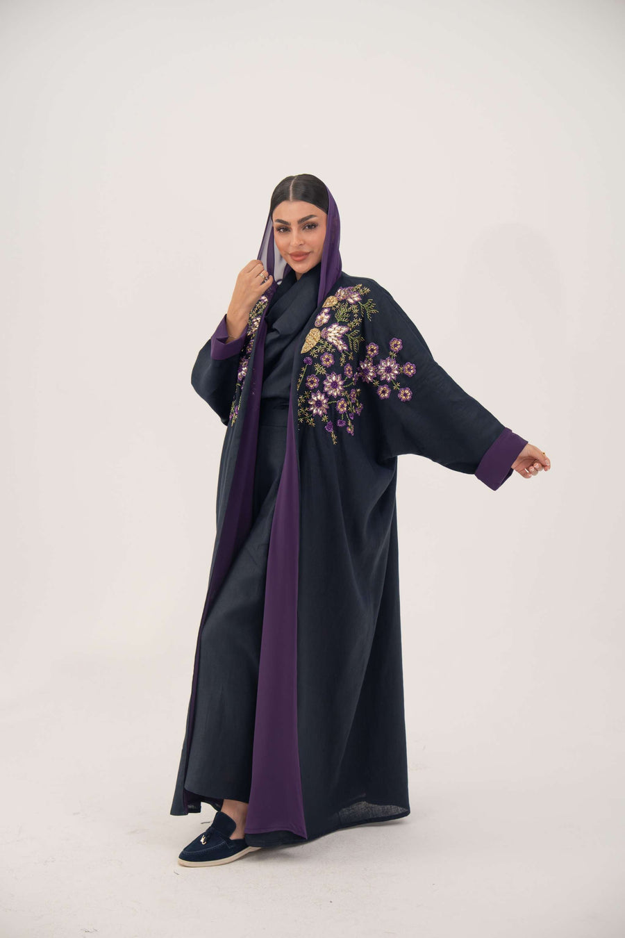 Navy blue linen-blend abaya with purple, gold, and green hand-stitched floral details and wide bisht style with purple cuffs and chiffon lining.