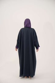Back view of a navy blue linen-blend abaya with purple cuffs and a matching inner border, featuring a loose bisht style and lightweight lining.