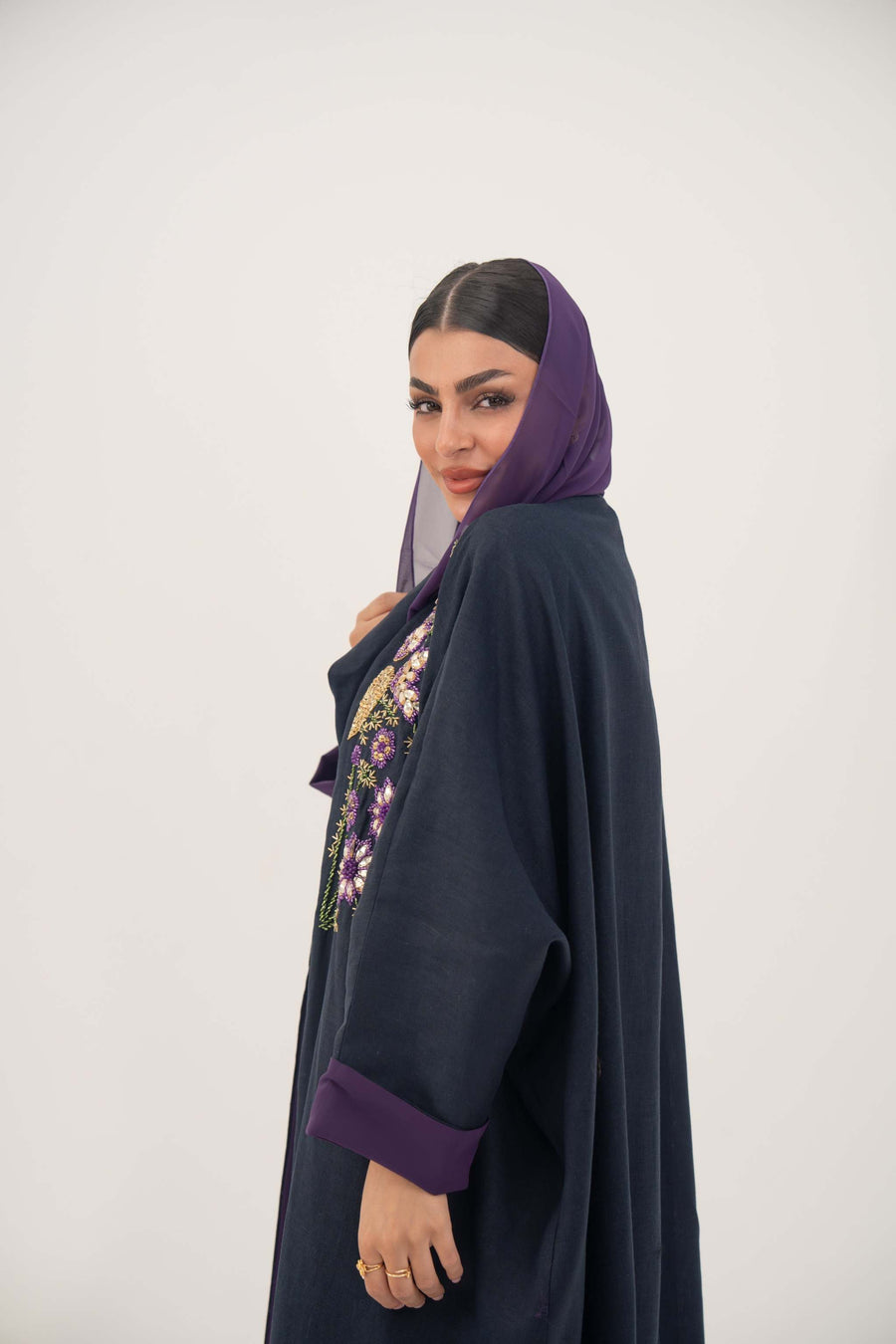 woman wearing navy blue linen-blend abaya with colorful hand-stitched details and purple cuffs