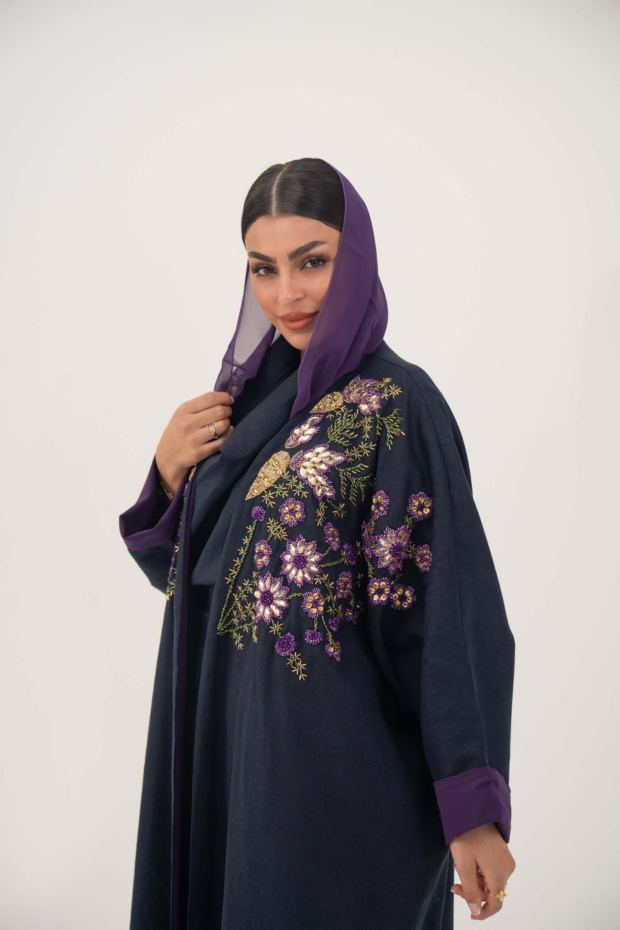 woman wearing navy blue linen-blend abaya with purple, gold, and green hand-stitched floral embroidery and purple cuffs