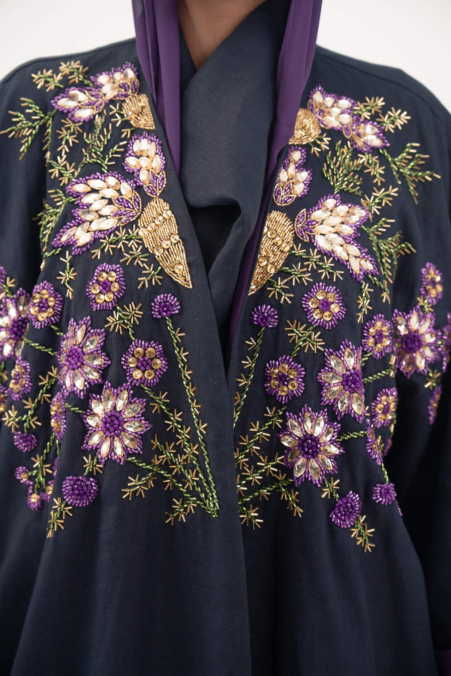 close-up of navy blue linen-blend abaya with intricate purple, gold, and green hand-stitched floral embroidery