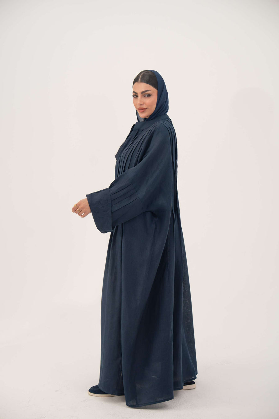 Woman wearing full-length open-front abaya navy blue linen with vertical stitched pleats